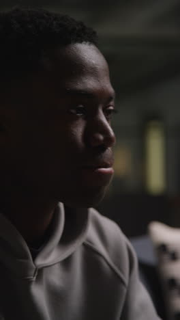 vertical video close up shot of unhappy and depressed young man sitting on sofa shaking head and shouting 2