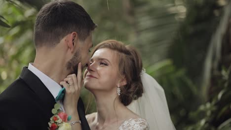 uma noiva e um noivo a beijar-se num jardim