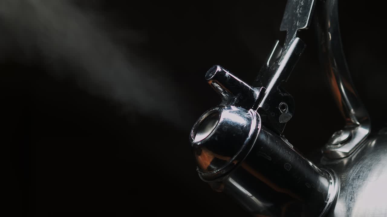 Vapor del pico de una tetera sobre fondo negro, primer plano dramático