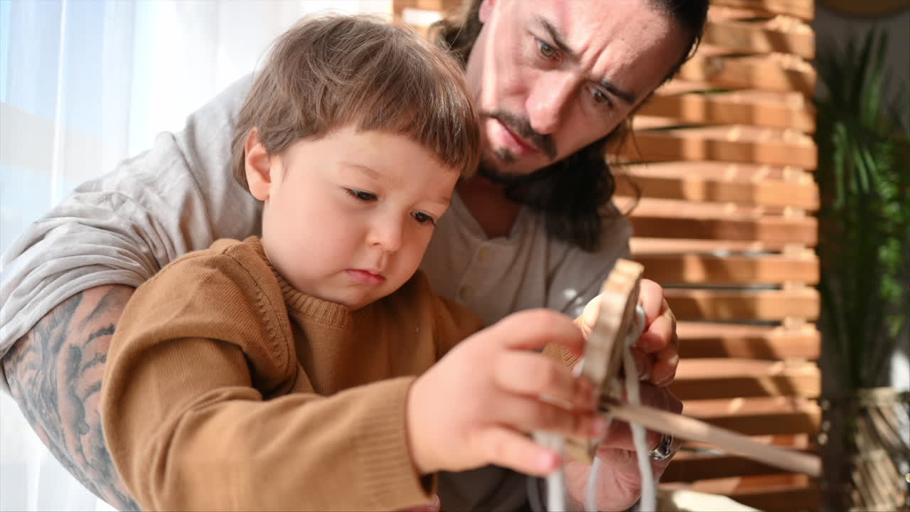 Father playing with his son with ecological wooden toys near the window