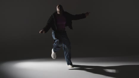 retrato de estudio de larga duración de una mujer joven bailando con iluminación de bajo tono contra un fondo gris 6