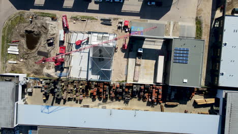 top down aerial of large crane on construction site on industrial area - drone lifting up