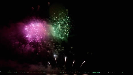 una mezcla estallante de luces brillantes de colores llenó el cielo nocturno en un festival de fuegos artificiales en una playa en el sureste de asia.