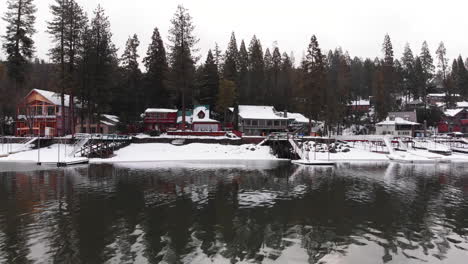 Pan-A-La-Derecha-Del-Lago-Brillante-En-Invierno,-Casas-Y-Muelles-En-La-Costa-Nevada