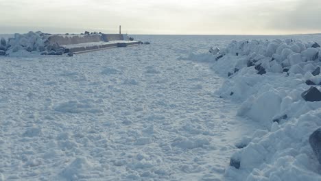 vuelo aéreo sobre tetrápodos cubiertos congelados junto al hielo marino a la deriva en el puerto de sawaki, hokkaido