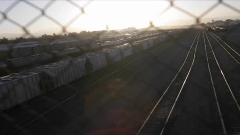 a time lapse shot through a chain link fence of a railway freight yard