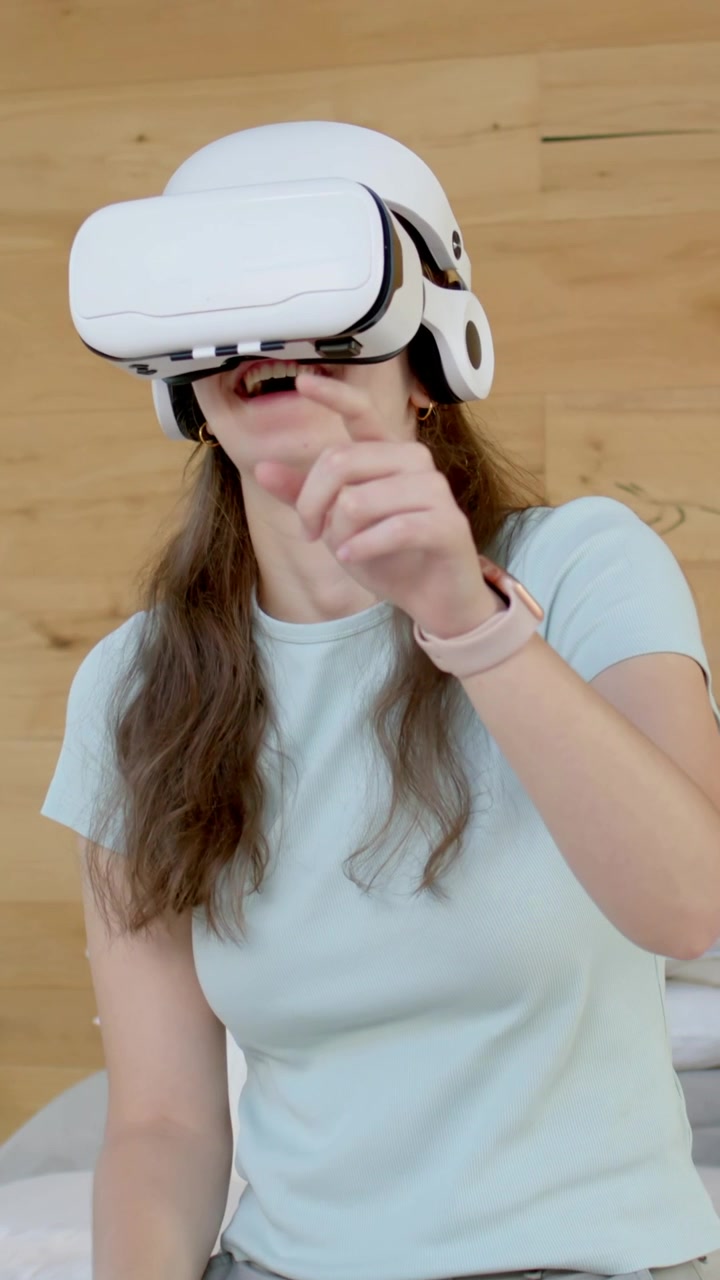 Video verticale: Visore VR bianco che si attiva, donna che indica e muove le mani in camera da letto giocando per divertimento.