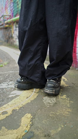 vertikal close-up-video im freien mode-shot zeigt junge alternative stil frau in hose und stiefeln in realzeit 1