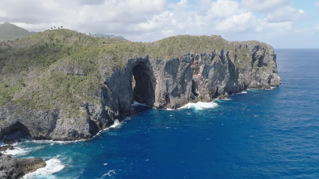 vista aérea de la cueva de la puerta en el parque nacional de cabo cabron con nubes en el cielo: olas chocando contra la costa rocosa