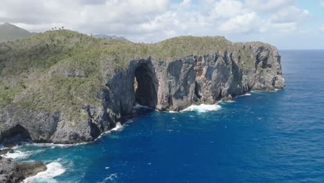 aerial view of la puerta cave in cabo cabron national park with clouds at sky - waves crashing against rocky coastline