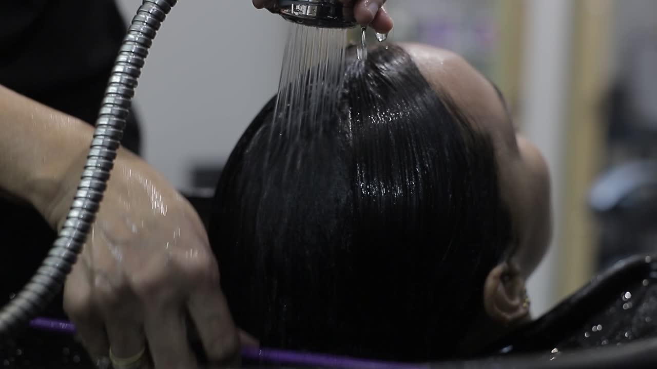 In un salone di bellezza, un parrucchiere pettina i capelli bagnati di un cliente con un massaggio