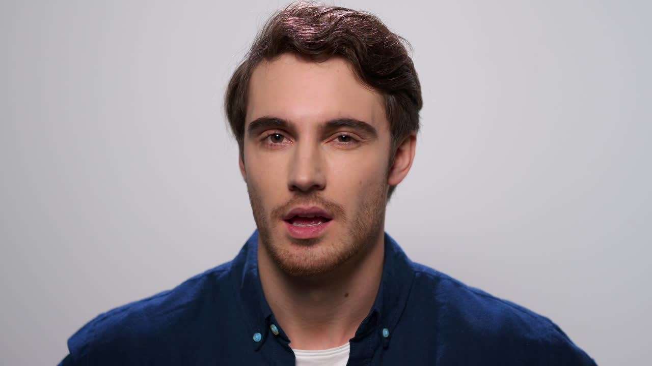 Man winking eye on light background. Male model flirting with camera