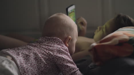 baby girl is attracted with brothers tablet computer