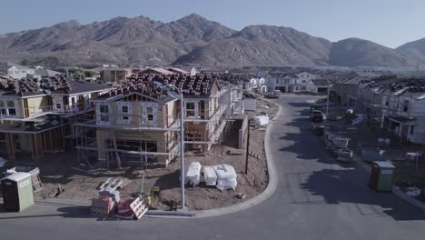 con un ritmo deliberado, un dron inspecciona de cerca una casa parcialmente construida en un sitio de construcción desde una distancia media, proporcionando una visión detallada del progreso en curso en el desarrollo residencial