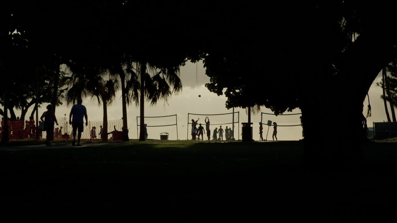 Silhouettes of people playing volleyball at sunset
