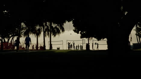 silhouettes of people playing volleyball at sunset