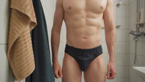 hombre revisando su área genital echando un vistazo dentro de sus calzoncillos en un baño