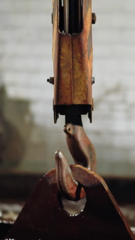 un gancho de grúa oxidado en equilibrio por encima del agua en un tanque de extinción en una fundición industrial de arena