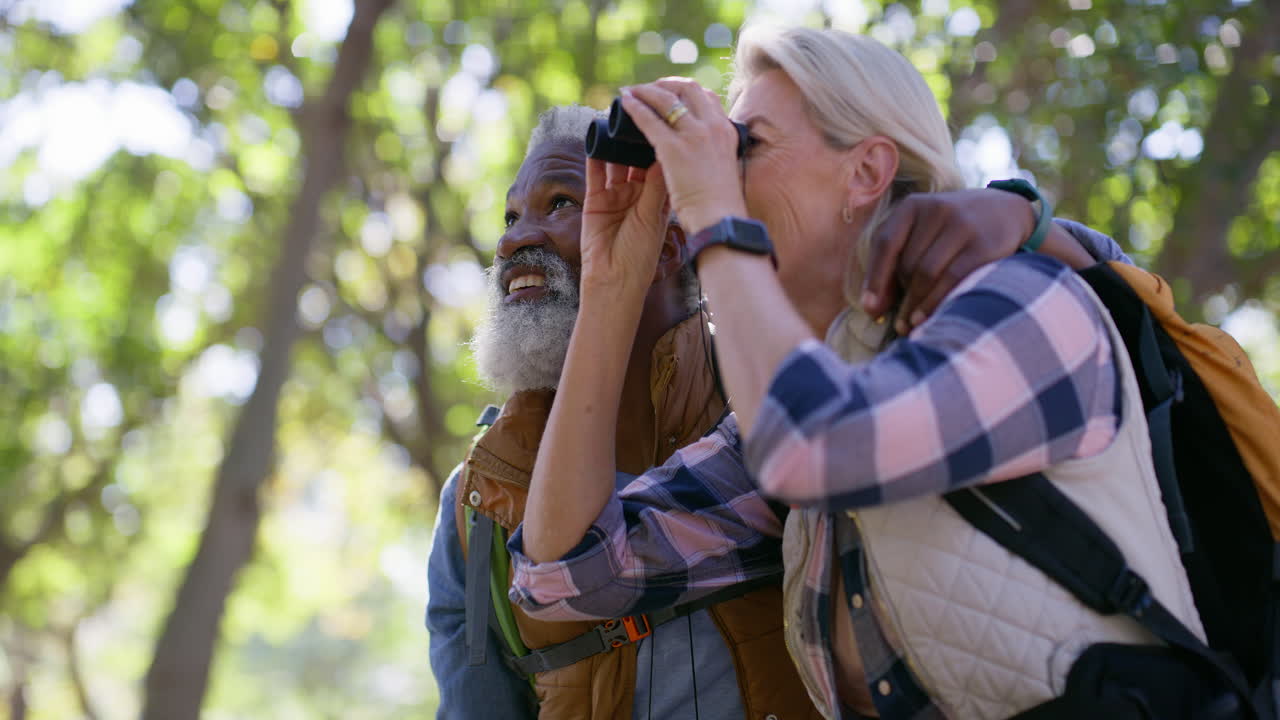Senior couple hiking and observing nature with binoculars