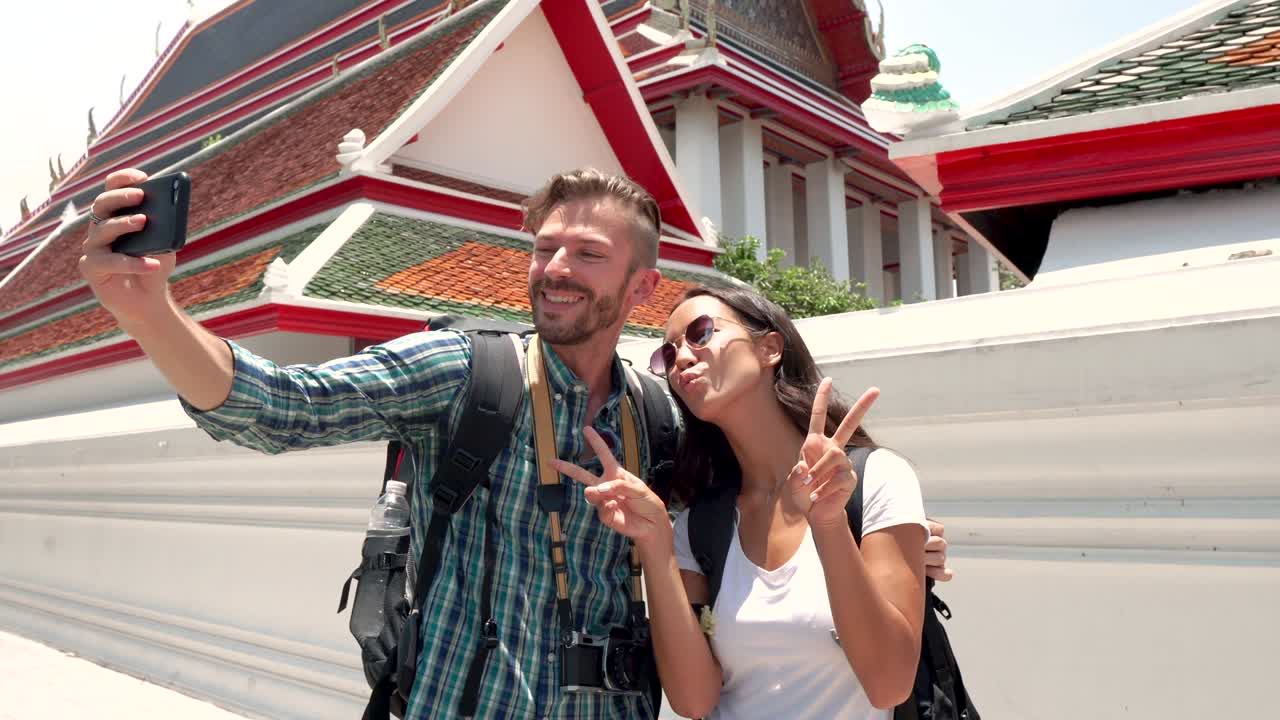 Coppia di turisti che si scatta un selfie con lo smartphone in un tempio thailandese in Thailandia