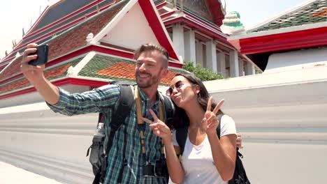 tourist couple taking selfie with smartphone at thai temple in thailand