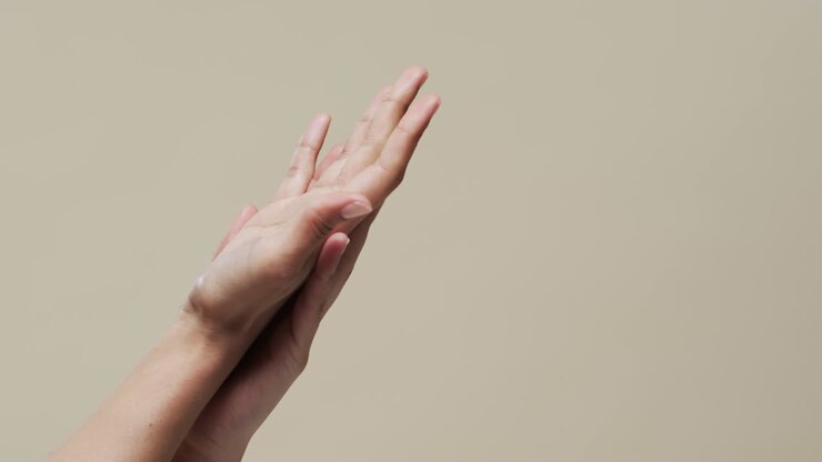 Mani di donna asiatica su sfondo beige con spazio per il testo, al rallentatore