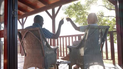 una feliz pareja afroamericana de alto nivel bebiendo vino en una terraza soleada, cámara lenta