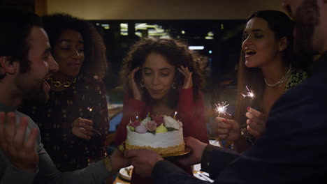 birthday girl blowing cake burning candles on party. friends sing celebration.