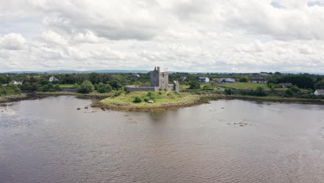 Toma-Aérea-Sobre-El-Agua-Acercándose-Al-Castillo-De-Dunguaire-En-El-Condado-De-Galway,-Irlanda