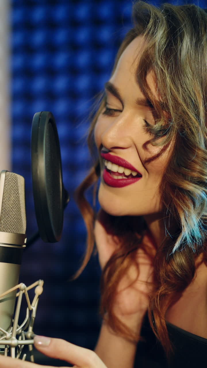 Vinnitsa, Ucraina - Maggio 2019: Giovane donna che registra una canzone in uno studio professionale. La ragazza canta nel microfono. Video verticale