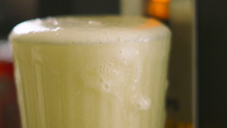 close up of excess lager foam overflowing and dripping down beer glass. cold chilled alcoholic drink