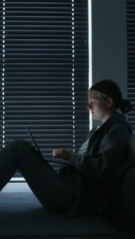 una adolescente usando una computadora portátil por la noche