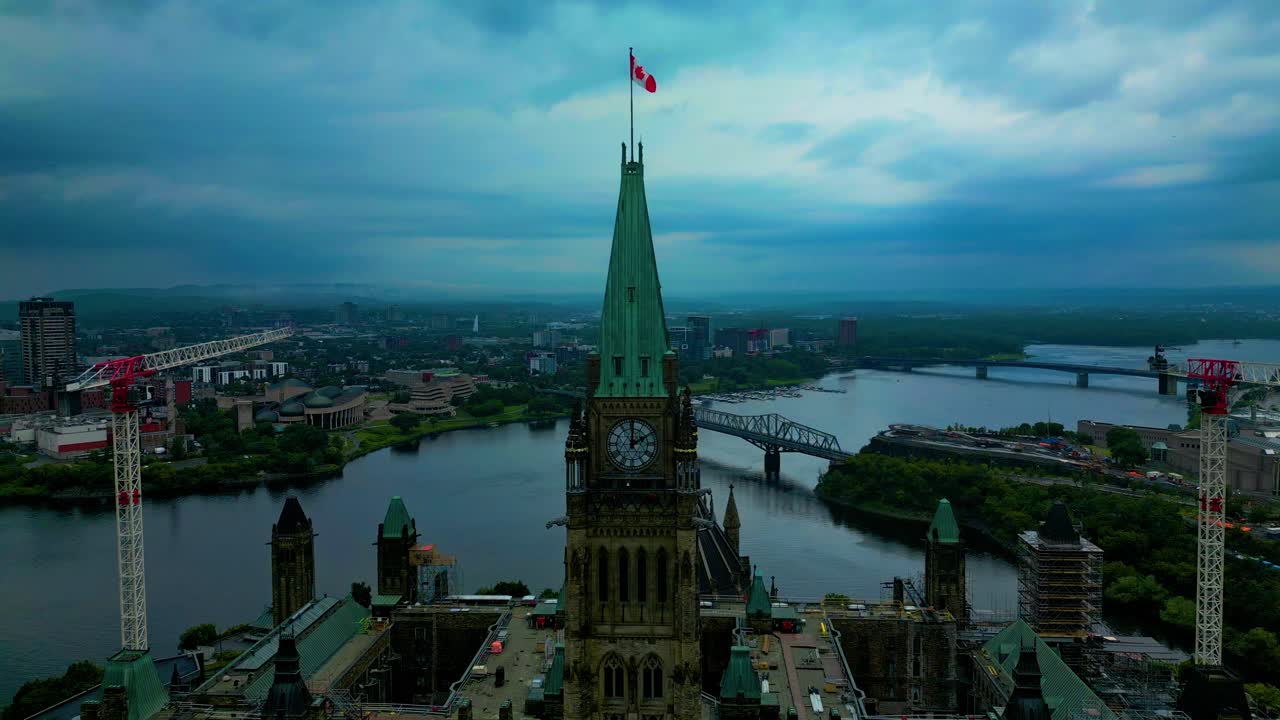 A detailed view of Parliament Hill's rooftop with a crane tower on each side of the building on a cloudy day aerial top view of Ontario bordering Quebec with the Ottawa river on a gloomy day 3-3