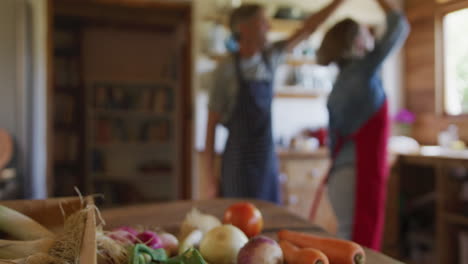 Sonriente-Pareja-Caucásica-Senior-Usando-Delantales-Y-Bailando-Antes-De-Cocinar-En-La-Cocina.