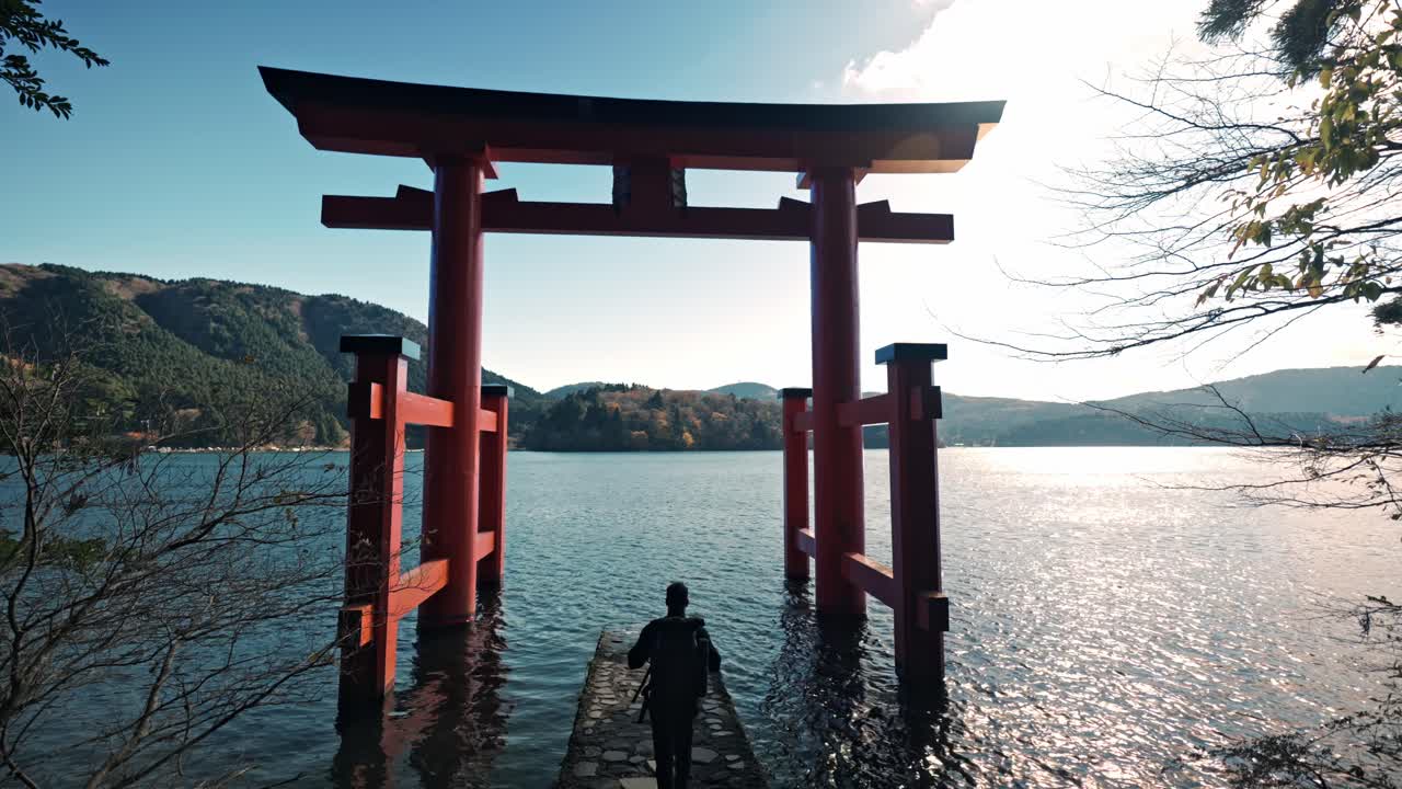 A cinematic video clip featuring a man walking through the peaceful grounds of Hakone Shrine, located by the picturesque Lake Ashi.