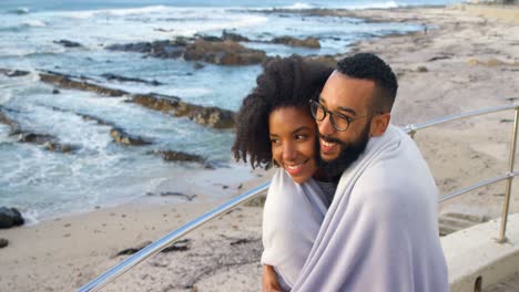 Couple-in-blanket-kissing-each-other-at-beach-4k