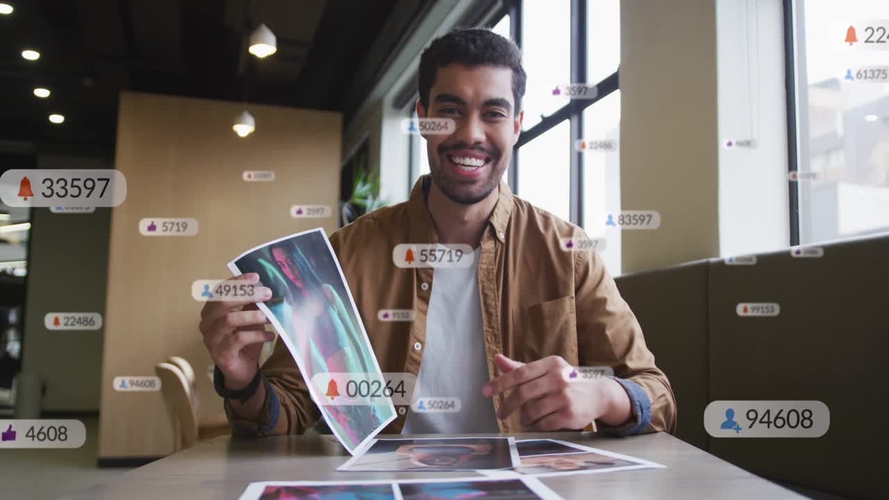 Content creator lifting print and showcasing work in cafe lounge, spawning rising social icons