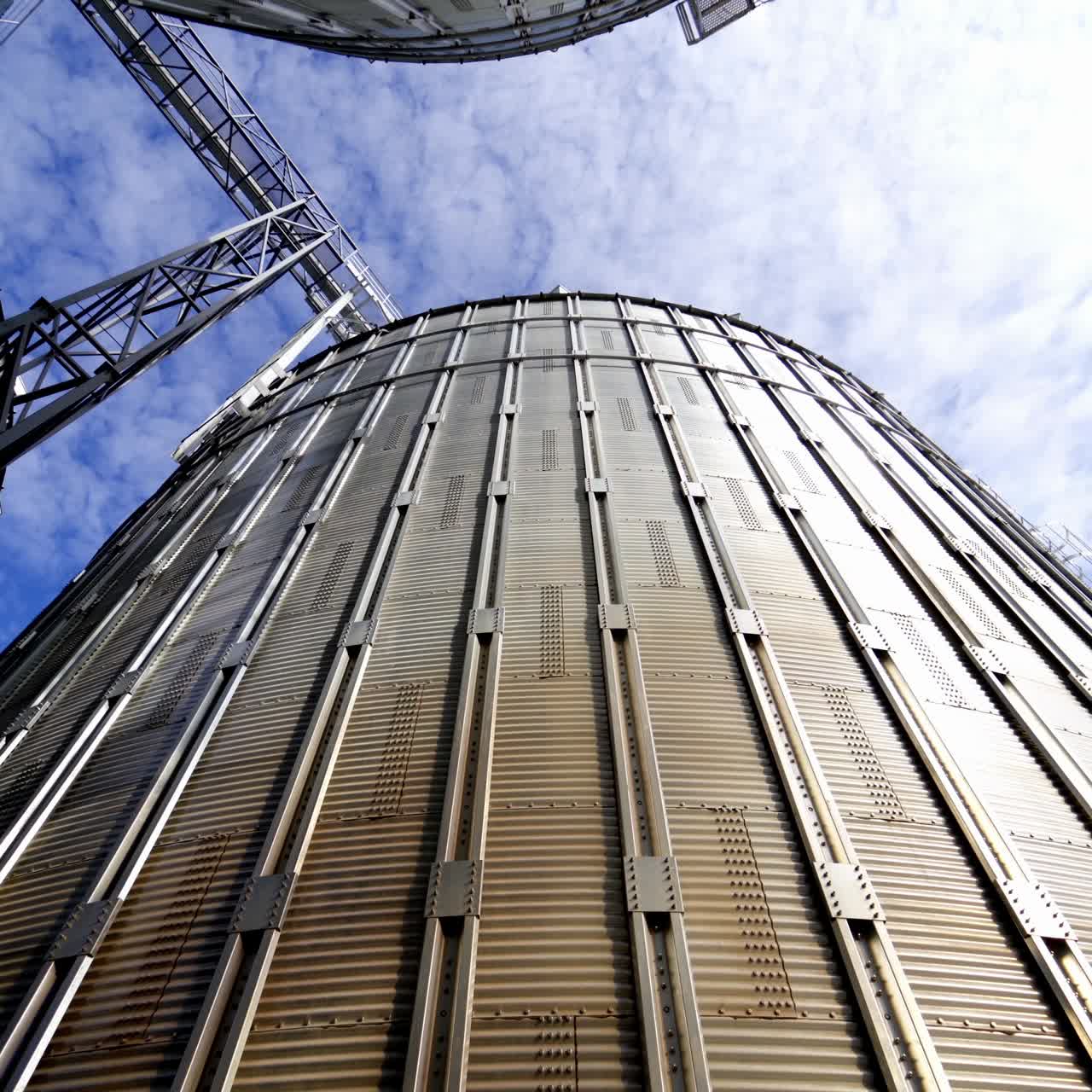 Granary grain elevators. Metal tanks for the storage crop. Large bins for farming. Aluminum containers against blue sky. Close-up.