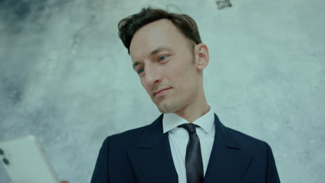 close up shot of executive senior businessman wearing black and white suit and checking his phone