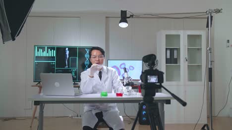 asian scientist man holding petri dish and talking to camera with professional lighting