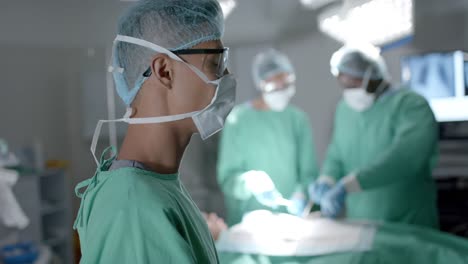 portrait of diverse surgeons with face masks during surgery in operating room in slow motion