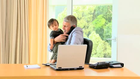 businessman holding toddler and working