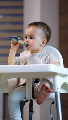 baby drinking juice pouch in high chair