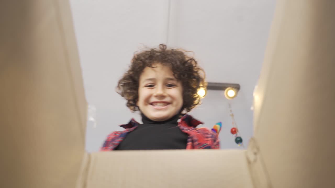 un chico lindo abriendo una caja de regalos y regocijándose y siendo feliz.