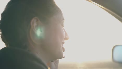 joyful lady sits in car holds black smartphone and chats