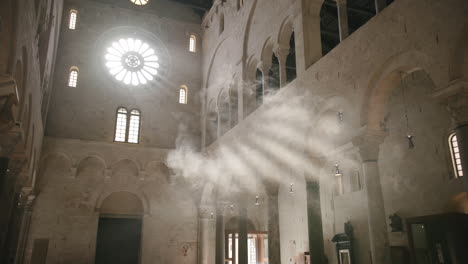 Slow-motion-footage-of-rays-of-the-sun-shining-through-a-window-of-a-church-illuminated-by-smoke-in-Bari,-Italy