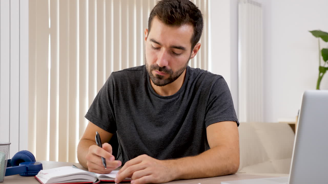 Man writing in notebook at desk