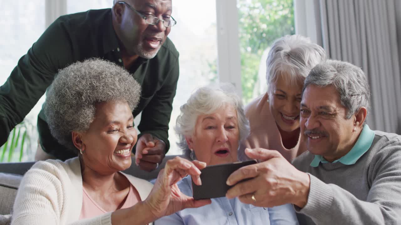 Group of diverse senior people using smartphone together at home