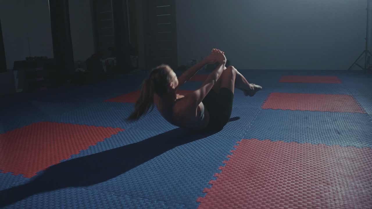 Donna in forma che allena gli addominali con esercizi a corpo libero in palestra.