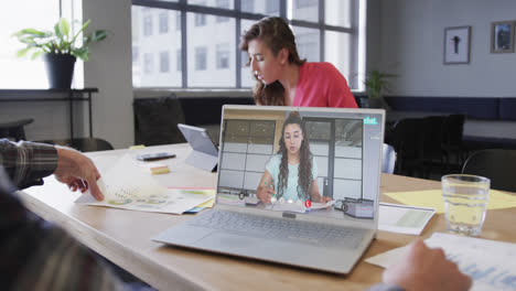 Caucasian-businessman-on-laptop-video-call-with-biracial-female-colleague-on-screen